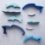 Wooden dolphin puzzle set in various shades of blue. The set includes a mixture of outlines and full-body shapes.