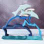Wooden dolphin puzzle set in various shades of blue. The set includes a mixture of outlines and full-body shapes. A combination of pieces are stacked together forming a dolphin diving scene.