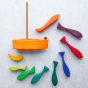 A wooden stacker set of various shapes, colours, and sizes of fish. The set includes a wooden boat with a sail. 