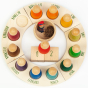Grapat English Perpetual Calendar displaying the 12 nin peg dolls in colours representing the months of the year according to Waldorf teachings. The display ring has each month written in English around the edge and two cubes in the centre to mark the day