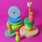 Grimm's Conical Stacking Tower - Neon Green - On a plain pink background. Grimm's Neon Mix Friends are in the foreground.