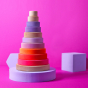 Grimm's Conical Stacking Tower - Neon Pink - On a plain pink background.