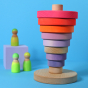 Grimm's Conical Stacking Tower - Neon Pink - On a plain blue background. Grimm's Neon Green Friends are in the background.
