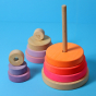 Grimm's Conical Stacking Tower - Neon Pink - On a plain blue background. The puzzle pieces are half on the stand and half off the stand.