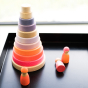 Grimm's Conical Stacking Tower - Neon Pink - In a home environment. Grimm's Neon Mix Friends are in the foreground.