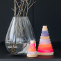 Grimm's Small Conical Stacking Tower and Grimm's Conical Stacking Tower - Neon Pink - Sit next to one another on a kitchen worktop. There is a vase in the background.