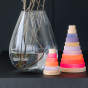 Grimm's Small Conical Stacking Tower and Grimm's Conical Stacking Tower - Neon Pink - Sit next to one another on a kitchen worktop. There is a vase in the background.