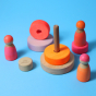Grimm's Small Conical Stacking Tower - Neon Pink - On a plain blue background. Grimm's Neon Pink Friends are in front and to the side of the Tower. The tower is in separate pieces.