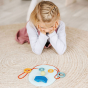 Young girl kneeling down and looking at a face made with some Grimm's plastic-free wooden toy blocks