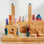 Grimm's wooden peg doll figures stood on top of a stack of Grimm's natural wooden toy blocks