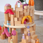 Grimm's plastic-free Waldorf toy blocks stacked into a tall tower on a grey floor