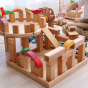 Grimm's large stepped pyramid Waldorf toy blocks stacked into a tower on a grey wooden floor