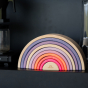 Grimm's 10-Piece Rainbow - Neon Pink- The top sits on a shelf in a home environment.