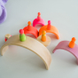 Grimm's 10-Piece Rainbow - Neon Pink- There are several sets of Grimm's Neon friends sitting on top of singular rainbow pieces.