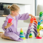 Grimm's 10-Piece Rainbow - Neon Pink. A child plays in her house with several sets of Grimm's Rainbows and Towers toys.