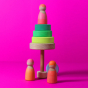 Grimm's Friends - Neon Pink - On a plain pink background. There is a small Neon Green Stacker Tower in the background. Two peg dolls stand at the base of the Tower and one stands on top.