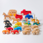 A collection of Grimms moving vehicles and toys including a bus, horse and carriage, small cars, race cars and boats in various colours and natural wood colours