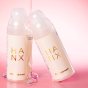 2 bottles of Hanx water-based lubricant on a pink background, covered in lubricant