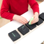 Childs hands writing numbers on the Hellion Toys plastic-free wooden chalk cubes on a white table