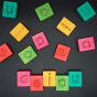 Hellion Toys sustainable multicoloured wooden vowel blocks scattered on a black background