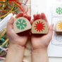 Childs hands holding Hellion Toys handmade wooden temperature blobs above some coloured paper strips