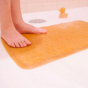 Close up of a child's feet stood on the Hevea plastic-free rubber bath mat next to a little rubber duck toy