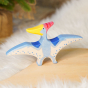 Holztiger Pteranodon pictured on a wooden play platfornm with white fluffy fabric behind. A blue flying dinosaur figure with handpainted details, a red crest and yellow beak.