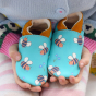 Inch Blue Leather Shoes with bees on being held in hands