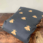 Integra navy bee cotton baby carrier folded on a wooden table