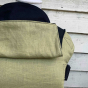 Close up of the organic linen Integra baby carrier in front of a wooden fence