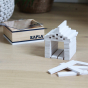 Close up of a small house made from white Kapla building blocks on a wooden floor