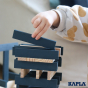 Close up of child's hand stacking the dark blue Kapla wooden blocks into a tower