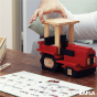 Close up of a hand stacking Kapla wooden toy blocks into the shape of a tractor on a wooden table