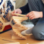 Close up of child stacking the eco-friendly Kapla wooden blocks in a spiral tower on a wooden floor