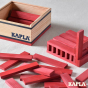 Close up of the Kapla red wooden construction blocks built into a house shape on a grey fabric background