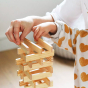 Close up of a child's hands stacking Kapla wooden building blocks in a geometric tower