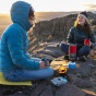 Two adults enjoying the sunset and laughing. Both are holding their Klean Kanteen Camping Mugs, on the left is the Dark Denim Mug, and on the right is the Red mug.