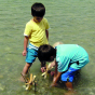 Children playing with the Kraul small waterwheel kit in a river.