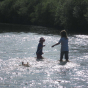 Two children pulling a Kraul Trout Paddle Boat behind them in a river.