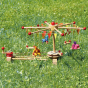 Kraul Wooden Swing Roundabout Kit with passenger dolls outside on the grass
