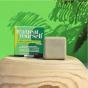 Picture of the Lamazuna Tea Treat Yourself Blemish Prone Skin Cleansing Bar with its green box, on a green background with plants.