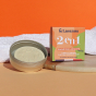 Lamazuna 2-in-1 Organic Shampoo and Body Wash bar, in a Lamazuna Metal Tin and next to the box, on an orange background with a white towel