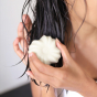conditioner bar being used on wet hair, being rubbed on by hands onto dark hair