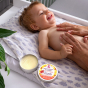 Picture of the Lamazuna Extra Gentle Baby Massage Butter in tin with lid off next to baby 