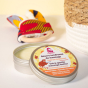 Picture of the Lamazuna Extra Gentle Baby Massage Butter in tin with lid off with baby toy in the background