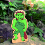 Close up of the plastic free lanka kade troll figure stood on a rock in front of a green plant