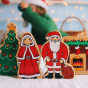 Lanka kade plastic free wooden mr and mrs claus toys stood on a white table in front of a lanka kade christmas tree and fire place