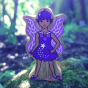 Close up of the Lanka Kade wooden bluebell fairy figure stood on some moss in the woods