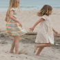 2 girls on a beach wearing the LGR organic cotton rainbow stripes and spots dresses