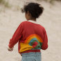 Close up of girl wearing the LGR red knitted cardigan with a rainbow design on the back